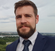 man in suit with river and city in the background